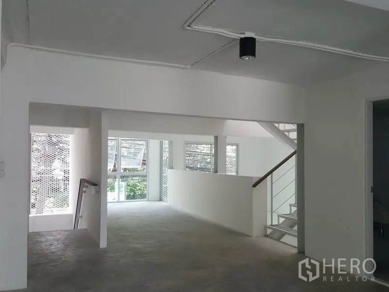 Home Office for rent in Khlong Toei, Bangkok - Mezzanine-style open office area with large windows and stair rail.