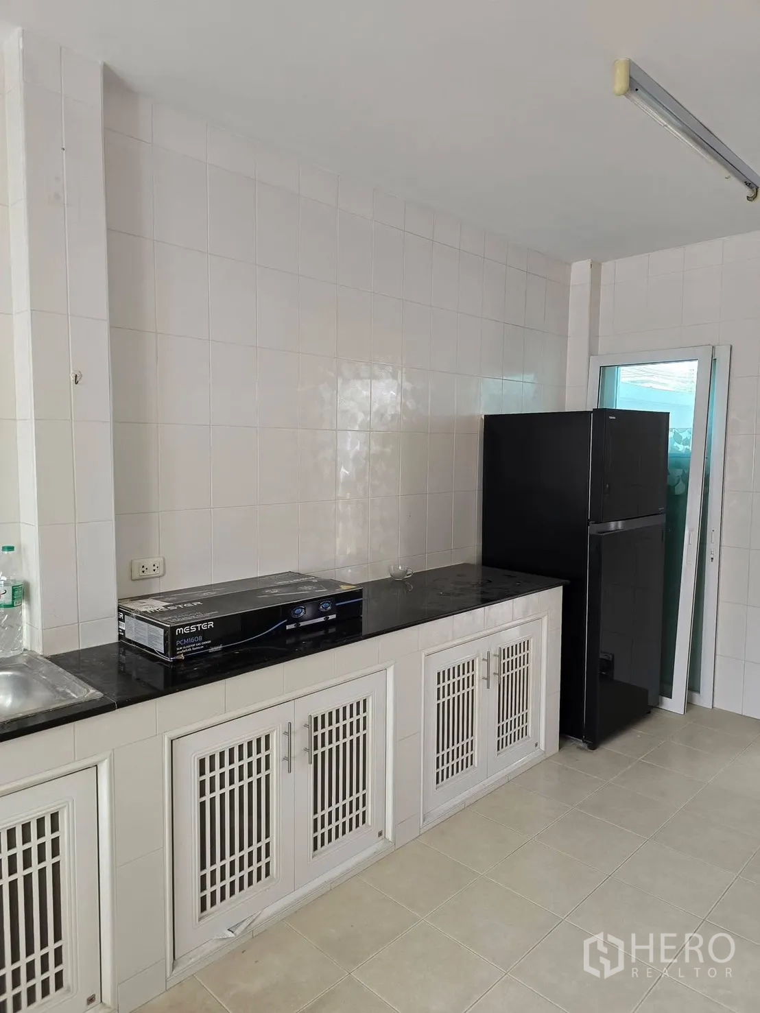 独栋房屋 for rent in Bang Phli, Samut Prakan - 瓷砖厨房，黑色台面、白色柜体和冰箱。