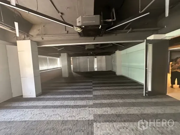 Office Space for rent in Khlong Toei, Bangkok - Open-plan office floor with striped carpet tiles, exposed ceiling and long side windows.