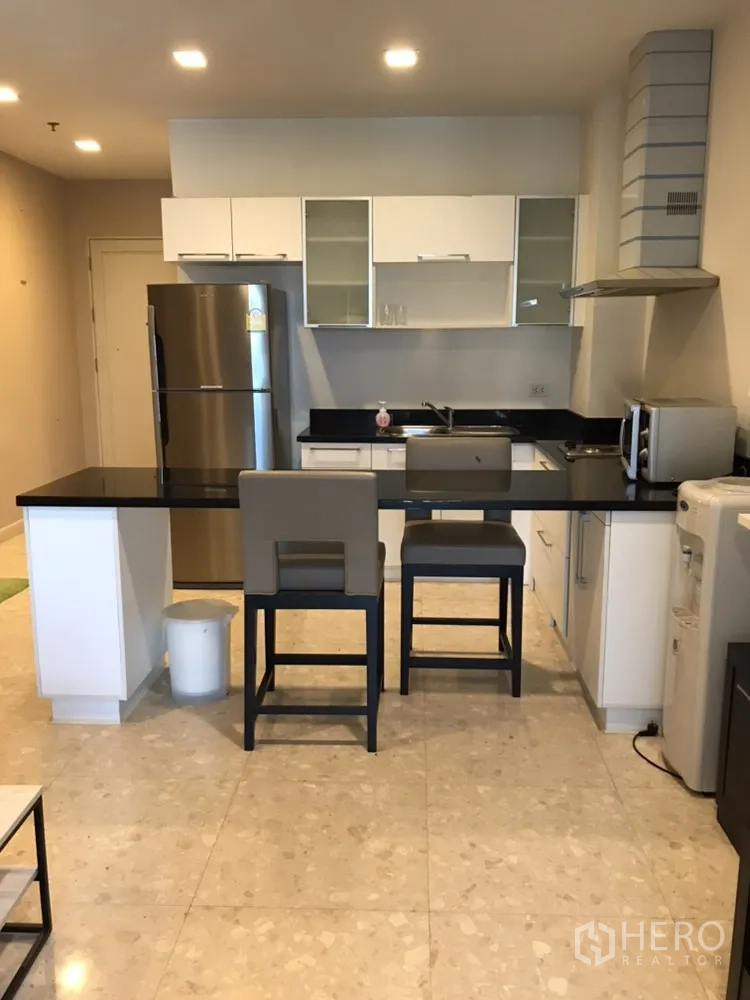 คอนโด ให้เช่าในKhlong Toei, Bangkok - ครัวโมเดิร์นเคาน์เตอร์หินสีดำ ตู้สีขาว ไอส์แลนด์พร้อมเก้าอี้ และเครื่องใช้สแตนเลส