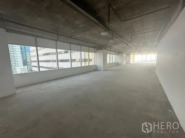 办公空间 出租在Watthana, Bangkok - 狭长工作区，两侧成排窗户，裸露混凝土天花与管道，两端采光充足。