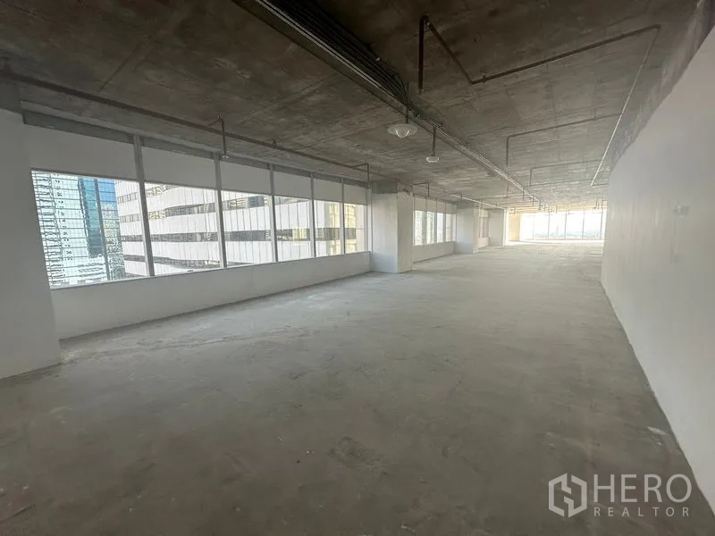 办公空间 出租在Watthana, Bangkok - 狭长工作区，两侧成排窗户，裸露混凝土天花与管道，两端采光充足。