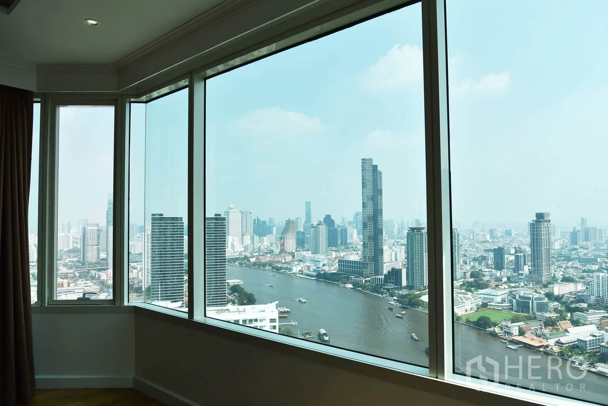 Condominium for sale in Khlong San, Bangkok - Large windows framing the Chao Phraya River and high-rise skyline from the interior.