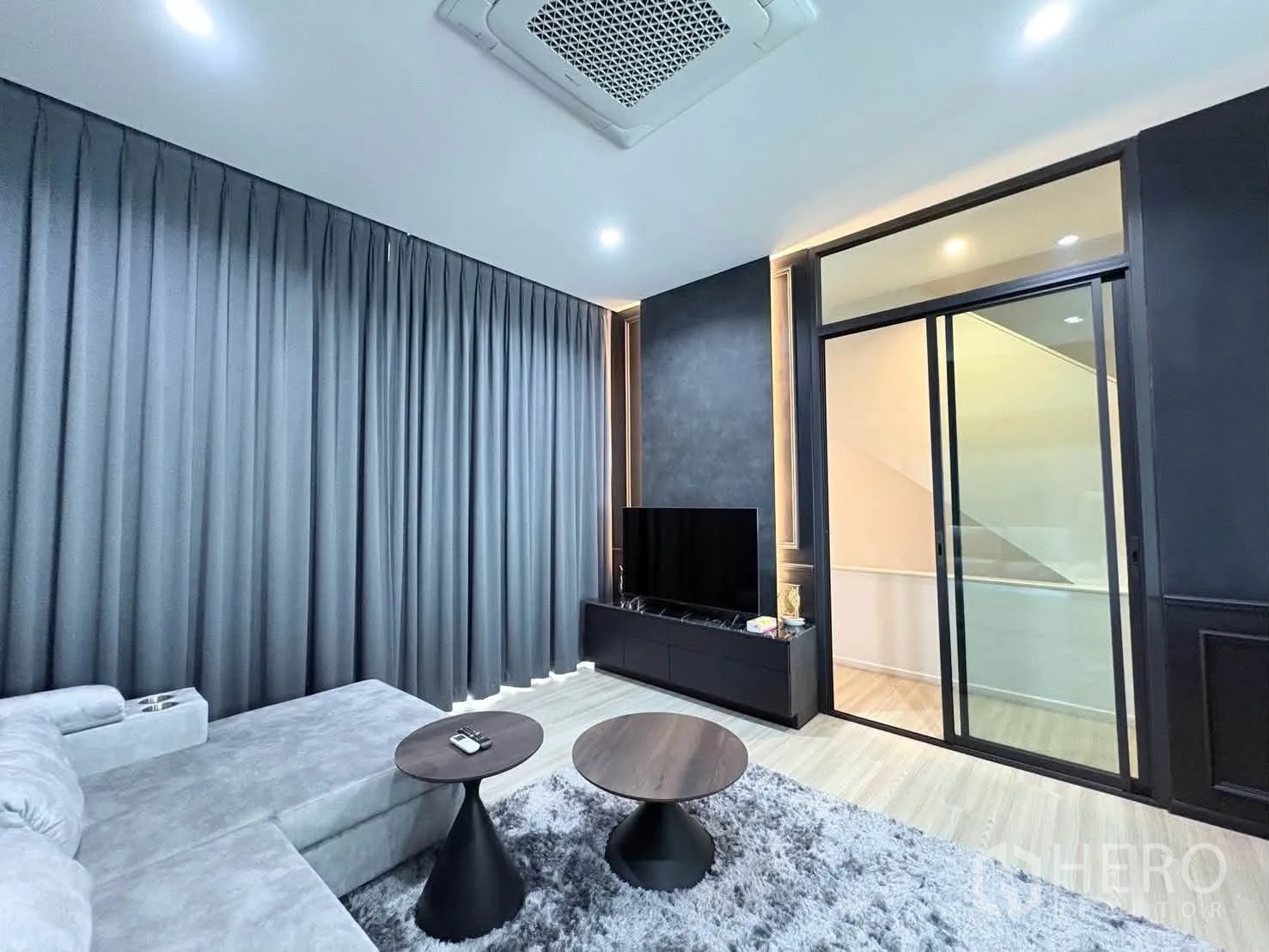 Detached House for rent in Saphan Sung, Bangkok - Cozy living room with large sectional sofa, TV console, sliding glass doors, and thick curtains.