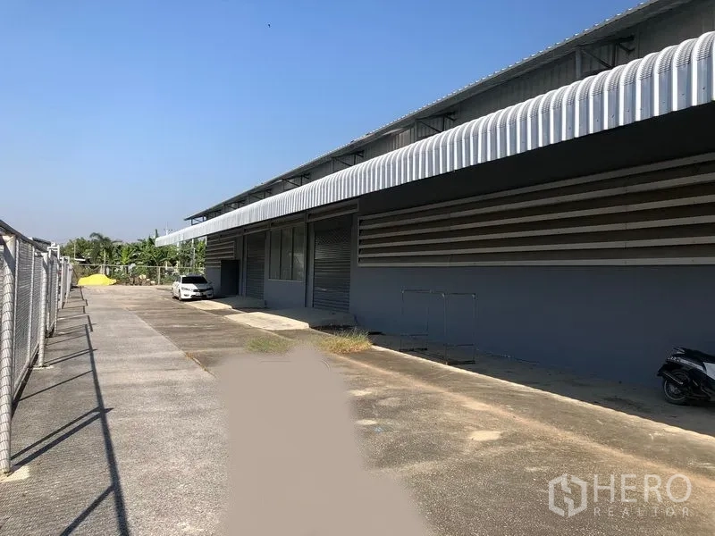 工厂 出租在Bang Bua Thong, Nonthaburi - 外立面一侧为加盖装卸月台、卷帘门及宽阔车道。