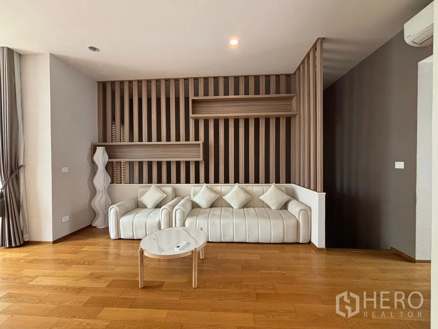 Townhouse for rent in Saphan Sung, Bangkok - Cozy lounge with a white sofa, wood feature wall, and round coffee table.