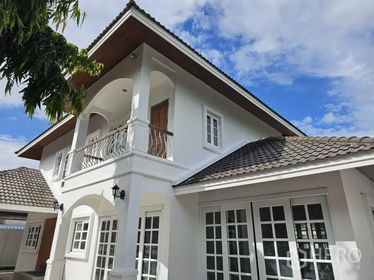 独立式住宅 出租在Phra Khanong, Bangkok - 外立面近景，拱形阳台、白墙与瓦屋顶的帕卡农独栋别墅