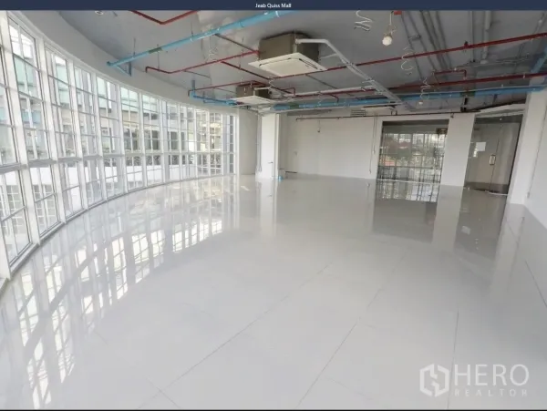 办公空间 出租在Khlong Toei, Bangkok - 开放式办公室，弧形落地窗环绕，亮面瓷砖地面与外露管线天花。