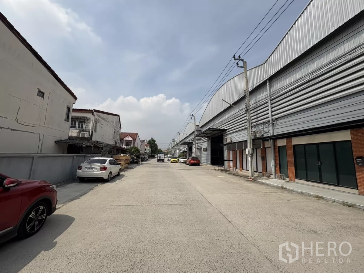 Warehouse for rent in Bang Phli, Samut Prakan - Street view of warehouse row and parking along a wide access road.