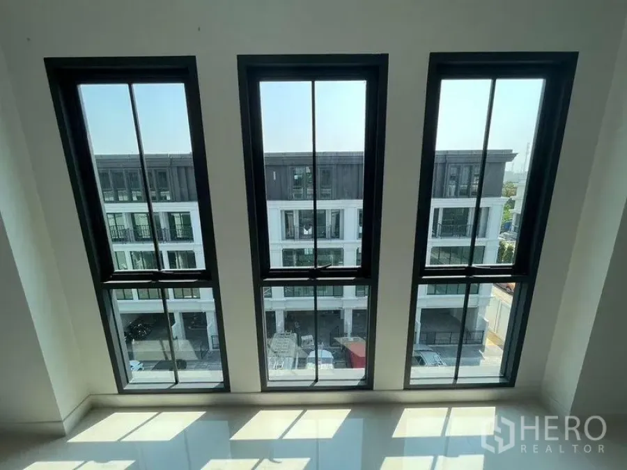 Home Office for rent - View through three tall windows to a modern townhouse row across the street.