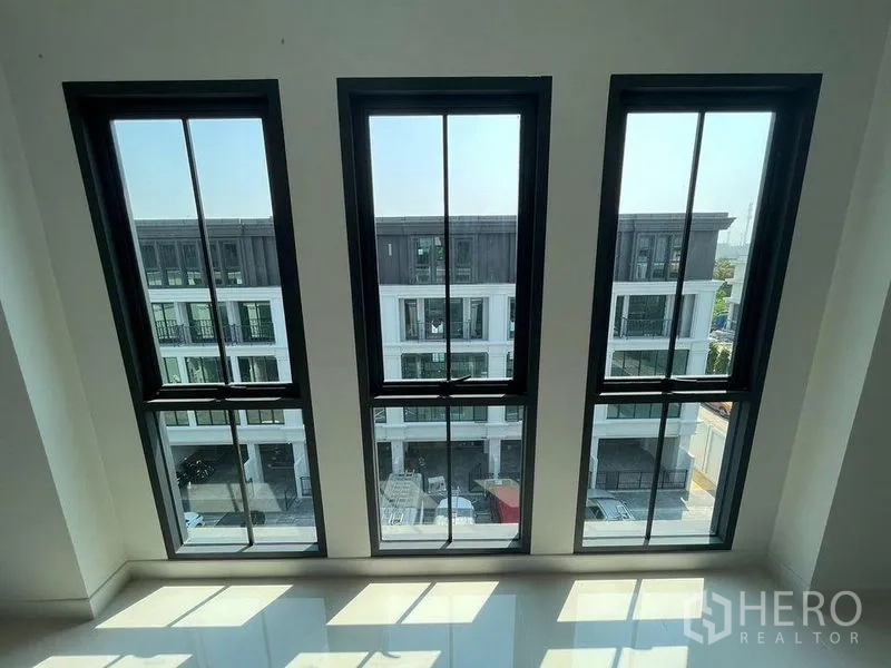 Home Office for rent - View through three tall windows to a modern townhouse row across the street.