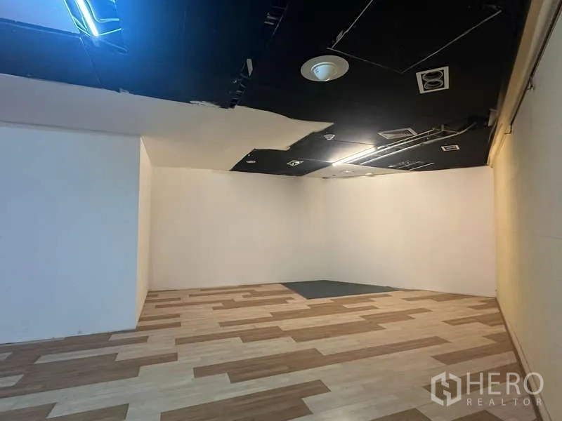 零售空间 出租 - 商铺角落区域，白色墙面、嵌入式灯光与通风面板。