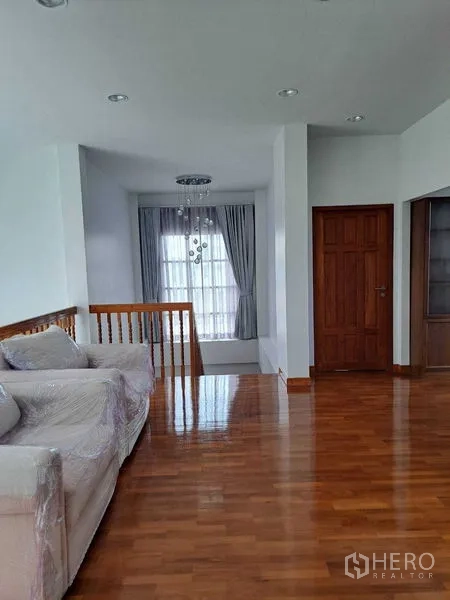 Detached House for rent in Prawet, Bangkok - Upstairs family lounge with sofa, wood floors and natural light from full-length window.