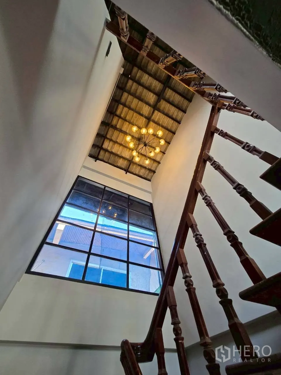 Detached House for rent in Phra Khanong, Bangkok - Double-height stairwell with chandelier and large grid window.