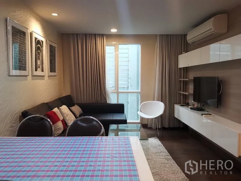 คอนโด ให้เช่าหรือขายในWatthana, Bangkok - พื้นที่นั่งเล่นแบบโอเพ่นพร้อมโต๊ะกลาง โซฟาสีดำ เก้าอี้สีขาว และชั้นวางทีวี