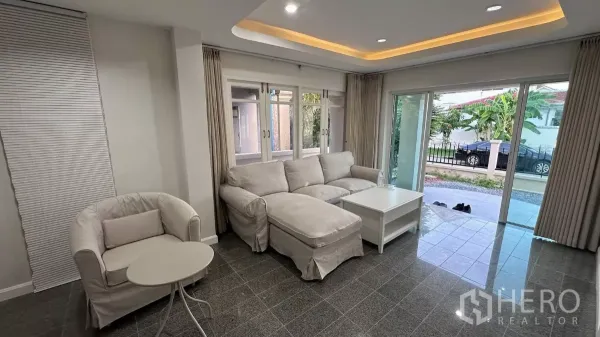 บ้าน ให้เช่าในLat Krabang, Bangkok - ห้องนั่งเล่นสว่างด้วยโซฟารูปตัวแอล ประตูกระจกบานเลื่อนและฝ้าเพดานไฟซ่อน