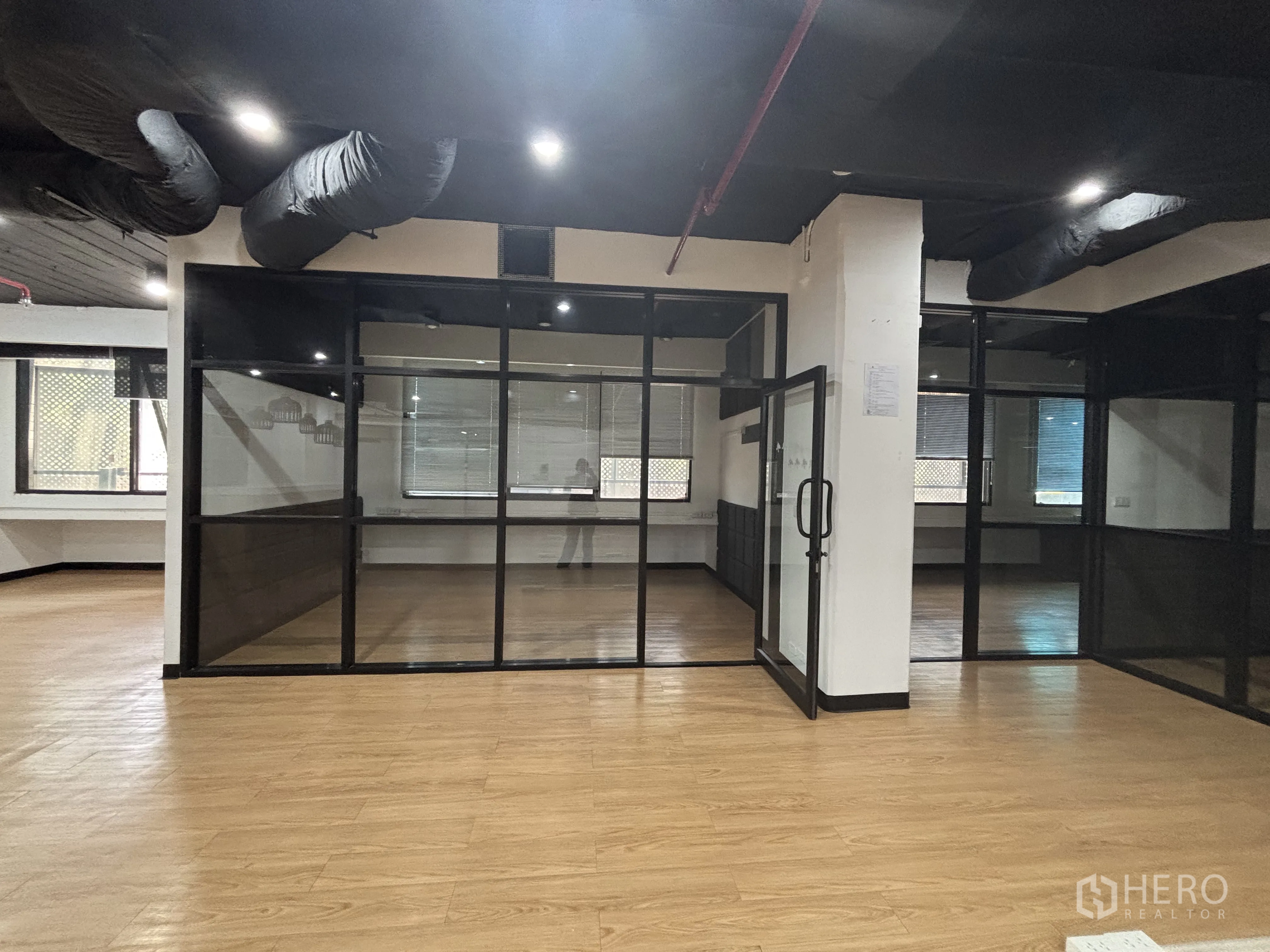 Office Space for rent in Bang Rak, Bangkok - Corner view of office showing multiple glass-walled rooms and wood flooring.