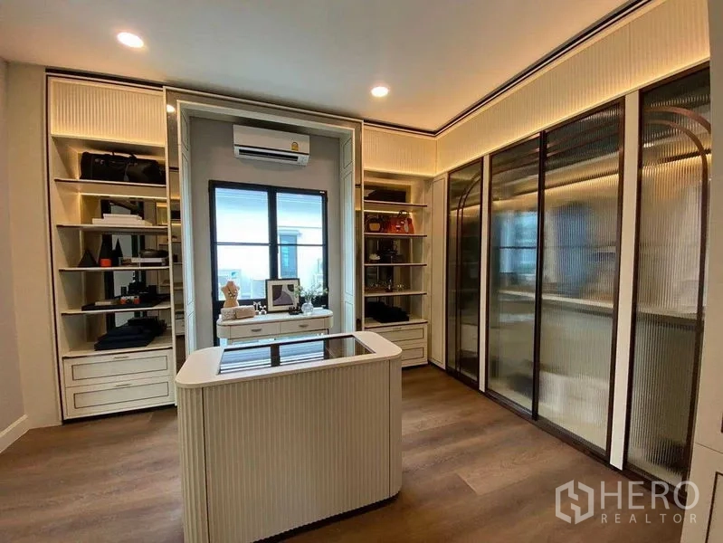 Detached House for sale in Saphan Sung, Bangkok - Dressing room with display island, illuminated shelves and fluted-glass wardrobes.