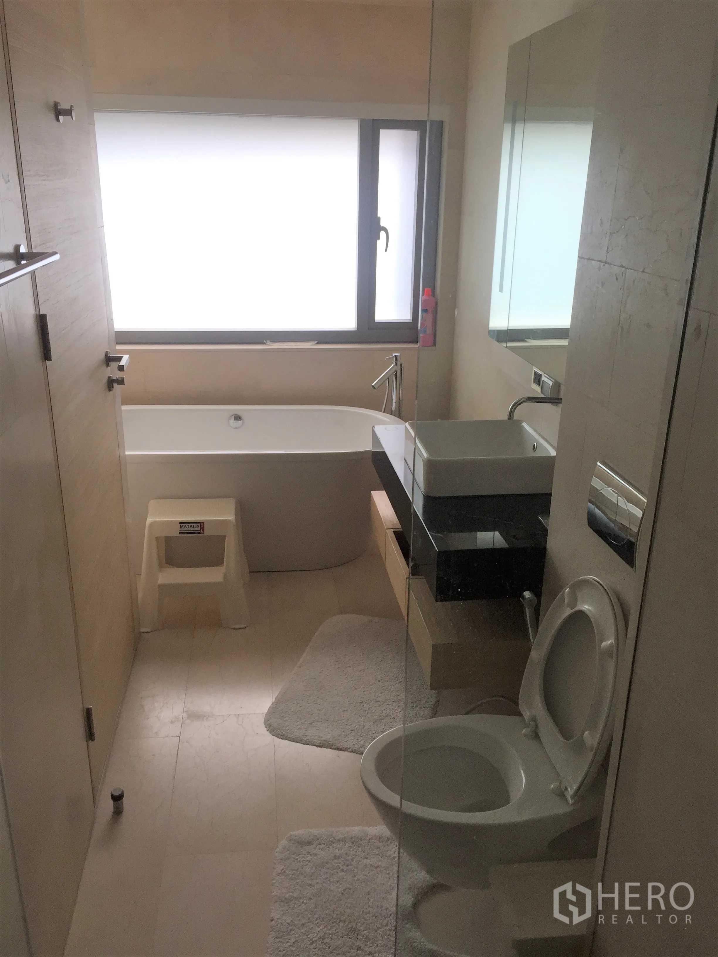 公寓 出租在Bang Rak, Bangkok - 浴室设浴缸、磨砂窗、壁挂式洗手台与坐便器。