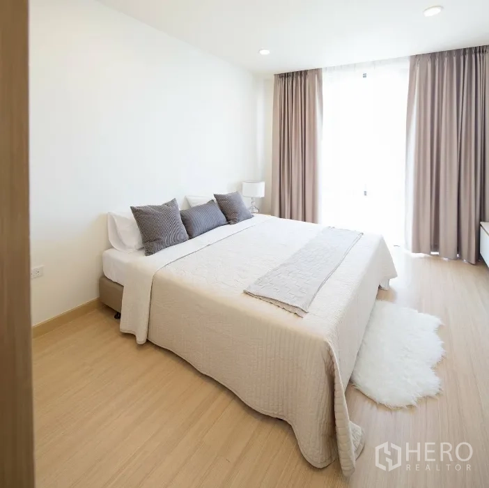 公寓 出租在Watthana, Bangkok - 第二卧室带大窗、米色窗帘与地毯，木质地板温暖舒适。