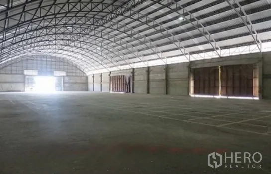 Warehouse for rent in Phra Pradaeng, Samut Prakan - Open-plan warehouse interior with high steel truss arch roof and smooth concrete floor.