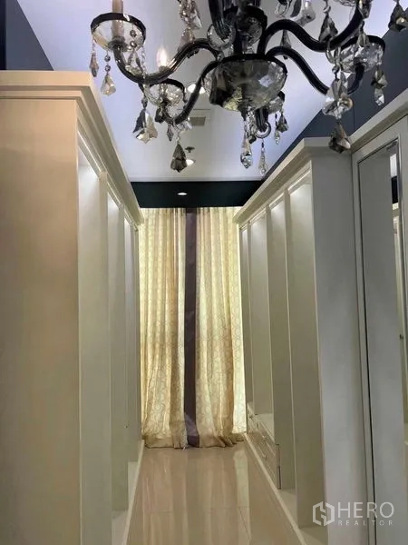 公寓 出售在Bang Na, Bangkok - 步入式衣帽间，水晶吊灯与白色嵌入式衣柜，落地窗帘。