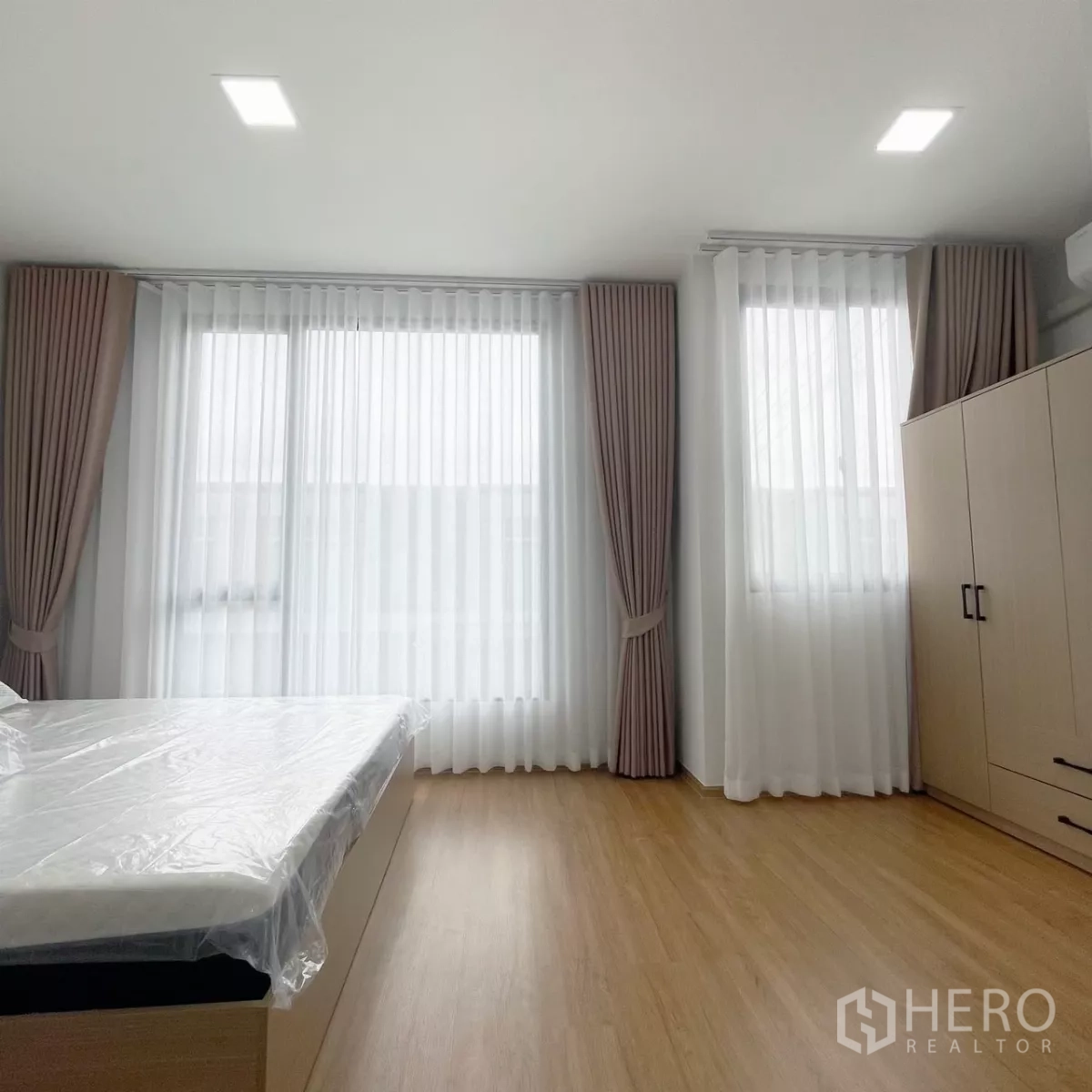 Townhouse for rent in Bang Phli, Samut Prakan - Spacious master bedroom with wood flooring, corner windows, sheer drapes and wardrobe.