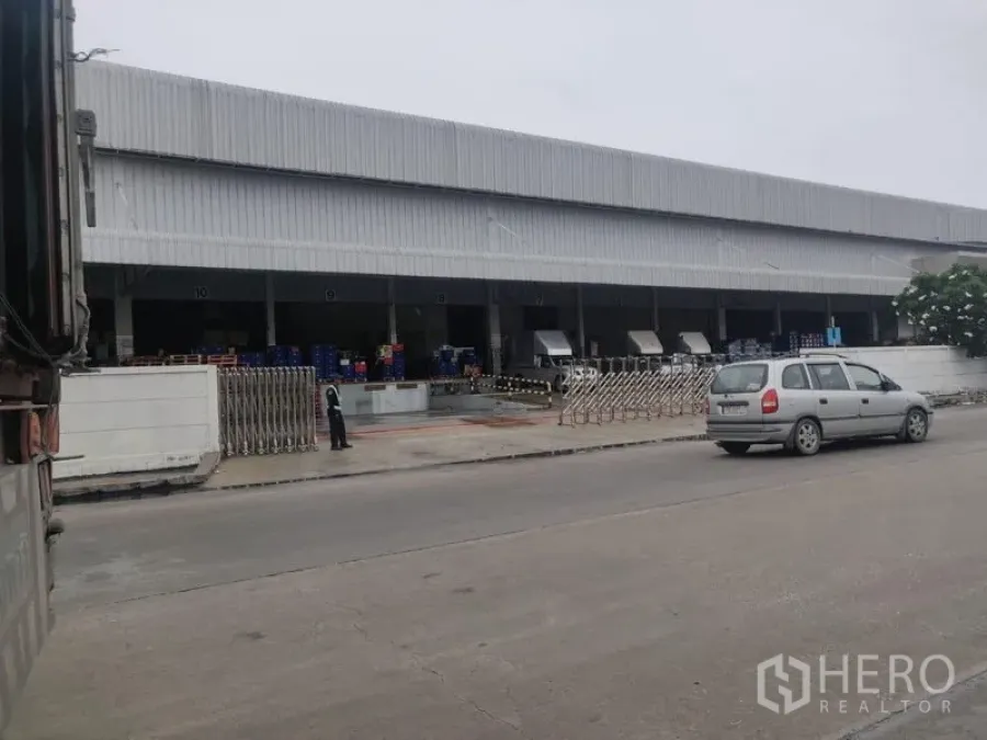 Warehouse for rent in Bang Phli, Samut Prakan - Front elevation of the warehouse showing dock bays and adjacent parking area.