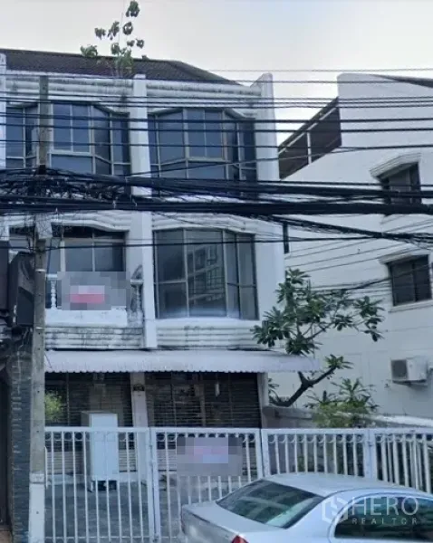 零售空间 出租在Watthana, Bangkok - 临街三层店屋外观，大面积凸窗与前院围栏，街头电缆可见