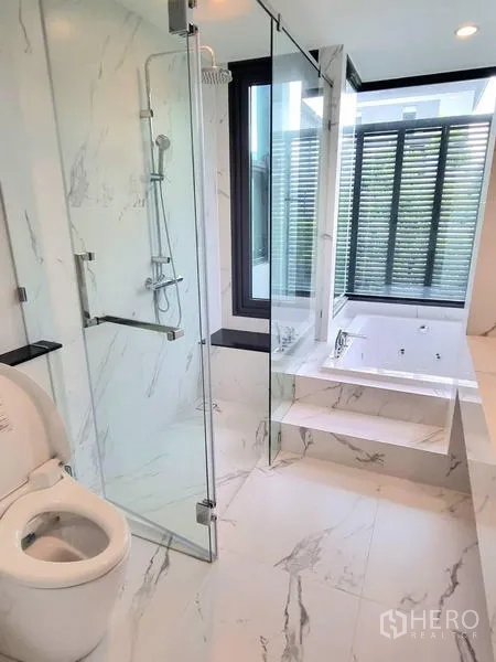 Detached House for rent - Bright marble bathroom with glass shower, toilet, and a step-up bathtub by the window.