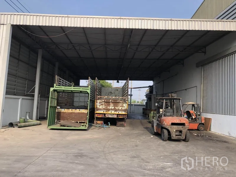 工厂 出租在Bang Bua Thong, Nonthaburi - 带高金属屋顶的覆蓋式装卸区，配有叉车和卡车。