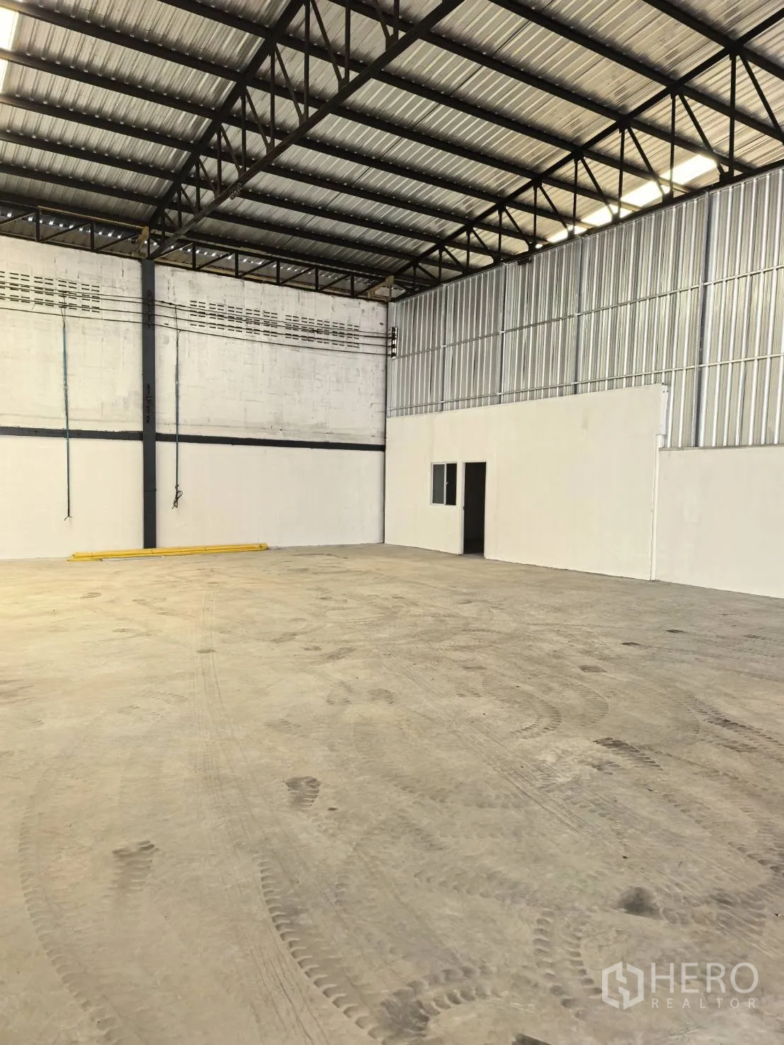 Warehouse for rent in Suan Luang, Bangkok - Wide interior shot showing open floor, internal office wall, and utility lines on the far wall.