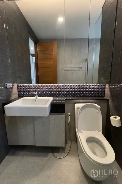 Semi-detached House for rent in Watthana, Bangkok - Contemporary bathroom with wall-mounted sink, toilet, and mirrored cabinet.