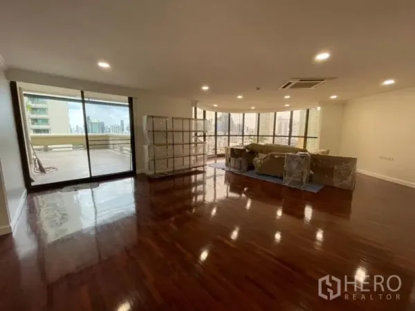 คอนโด ให้เช่าในKhlong Toei, Bangkok - ห้องนั่งเล่นกว้าง พื้นไม้เงา ไฟดาวน์ไลท์ ประตูกระจกบานเลื่อนเปิดสู่ระเบียงใหญ่เห็นวิวเมือง