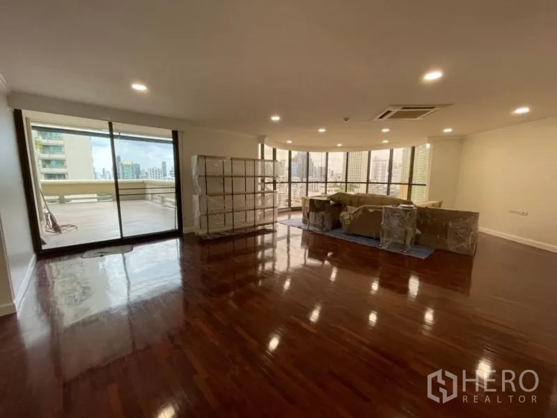 คอนโด ให้เช่าในKhlong Toei, Bangkok - ห้องนั่งเล่นกว้าง พื้นไม้เงา ไฟดาวน์ไลท์ ประตูกระจกบานเลื่อนเปิดสู่ระเบียงใหญ่เห็นวิวเมือง