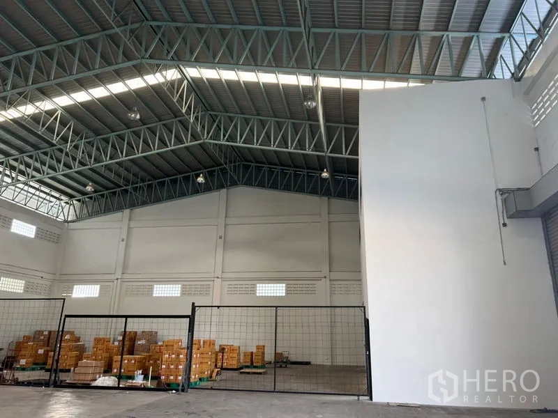 คลังสินค้า ให้เช่าในLat Krabang, Bangkok - โครงหลังคาโกดังสูงโปร่ง ผนังแกนสีขาว และพื้นที่กั้นตาข่ายพร้อมกล่องสินค้า