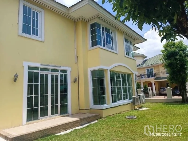 独立式住宅 出售在Prawet, Bangkok - 房屋后侧外观，大面积落地窗与草坪花园。