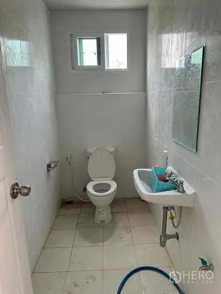 Warehouse for rent in Pak Kret, Nonthaburi - Clean tiled restroom inside the warehouse with toilet, sink and small window.