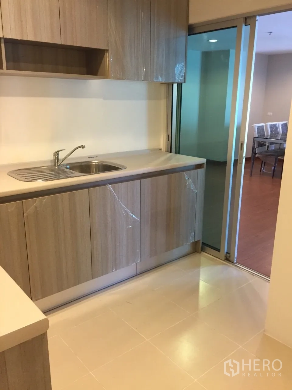 Condominium for rent in Huai Khwang, Bangkok - Separate kitchen with sliding glass door and ample storage connecting to the living area.