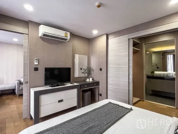 Condominium for rent in Pathum Wan, Bangkok - Bedroom with TV console and dressing table, plus sliding-door access to the ensuite bathroom.
