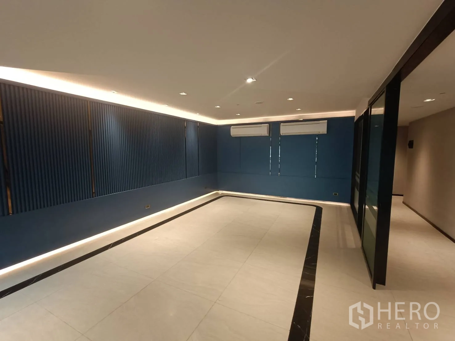 สำนักงานที่บ้าน ให้เช่าหรือขายในPhra Khanong, Bangkok - ห้องทำงานเปิดโล่ง ผนังตกแต่งสีน้ำเงิน แอร์สองเครื่อง และไฟรอบแนวผนัง