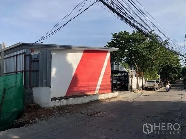 ที่ดิน ให้เช่าในPhra Khanong, Bangkok - มุมมองถนนด้านหน้าอาคารเตี้ยสีขาวคาดแดงและสายไฟฟ้า