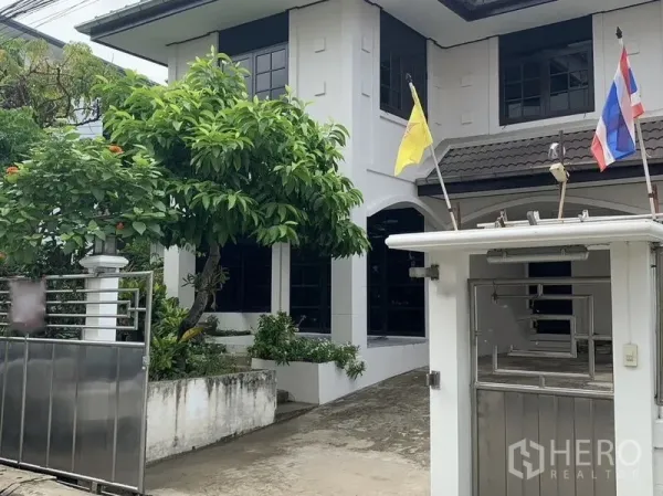 บ้าน ให้เช่าในKhlong Toei, Bangkok - ด้านหน้าบ้านเดี่ยวสองชั้น มีทางรถเข้าประตูรั้วและต้นไม้ใหญ่