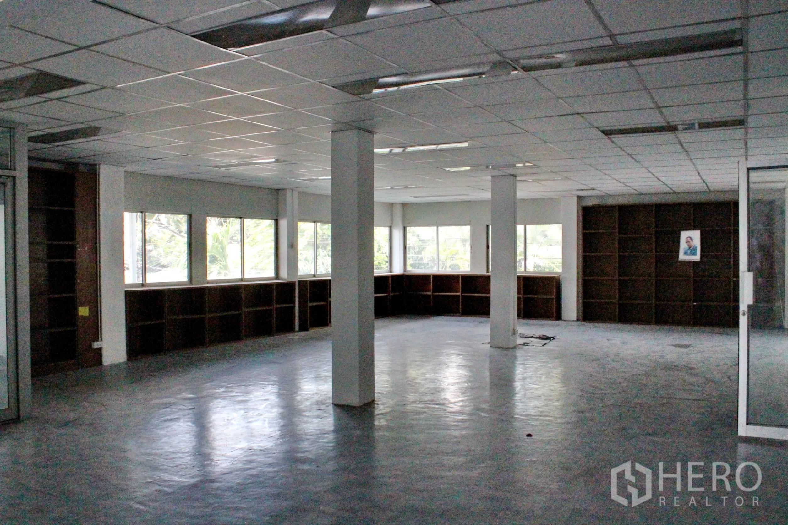 Home Office for rent in Khlong Toei, Bangkok - Spacious corner office with wraparound windows and built-in shelving units.