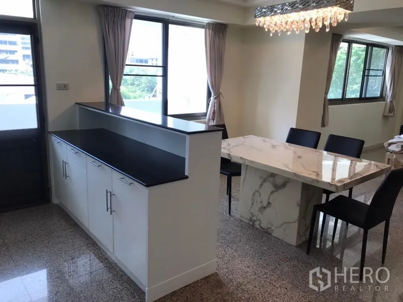 Condominium for rent in Watthana, Bangkok - Dining space with marble table, black chairs and corner windows with curtains.