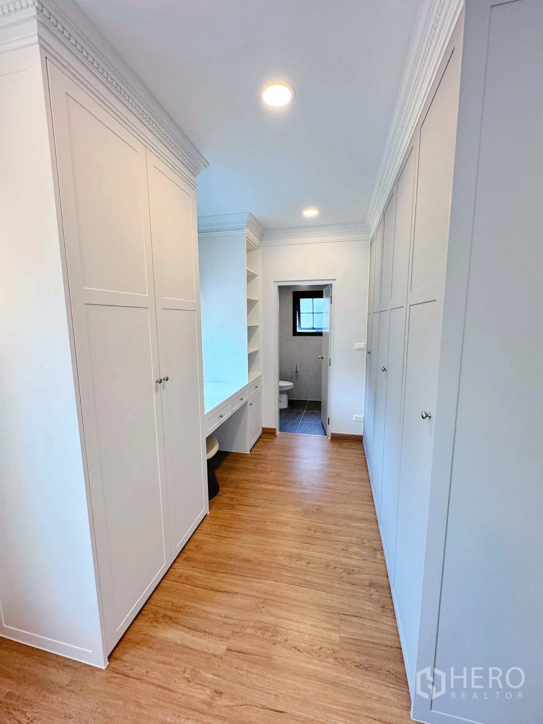 Detached House for rent in Bang Phli, Samut Prakan - Walk-in closet hallway with built-in wardrobes and vanity leading to bathroom.