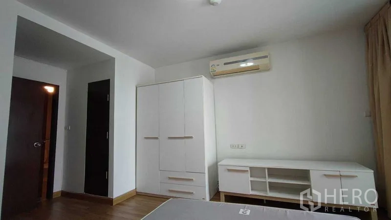 คอนโด ให้เช่าในKhlong Toei, Bangkok - ห้องนอนพร้อมตู้เสื้อผ้าสีขาว ตู้วางทีวี แอร์ และพื้นไม้