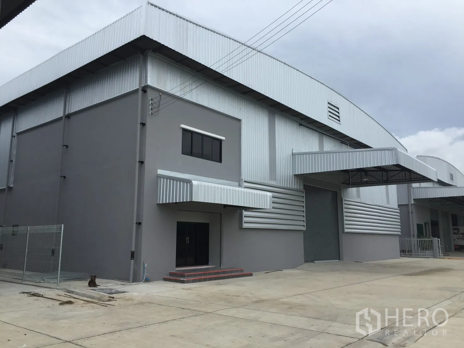 Warehouse for rent in Bang Phli, Samut Prakan - Row of warehouse bays with roller shutter doors and a wide driveway.