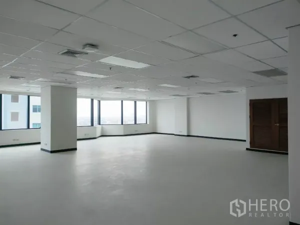 办公空间 出租在Huai Khwang, Bangkok - 宽敞转角办公区，环幕窗景、结构立柱与洁净地面。