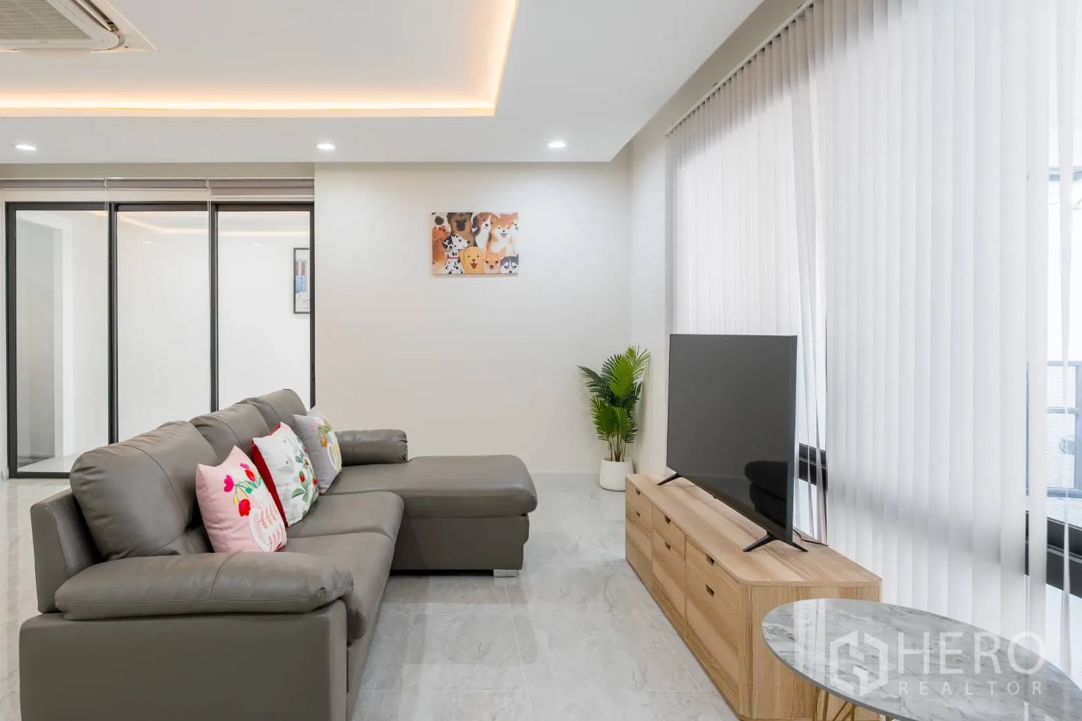 Home Office for rent in Khlong Toei, Bangkok - Cozy lounge with sectional sofa, TV console and full-height vertical blinds.
